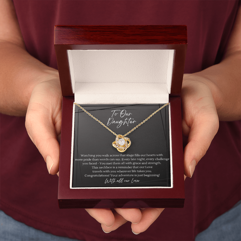 Parent holding graduation gift box with gold love knot necklace — luxury mahogany keepsake box with heartfelt "To Our Daughter" message card, meaningful jewelry gift for grad